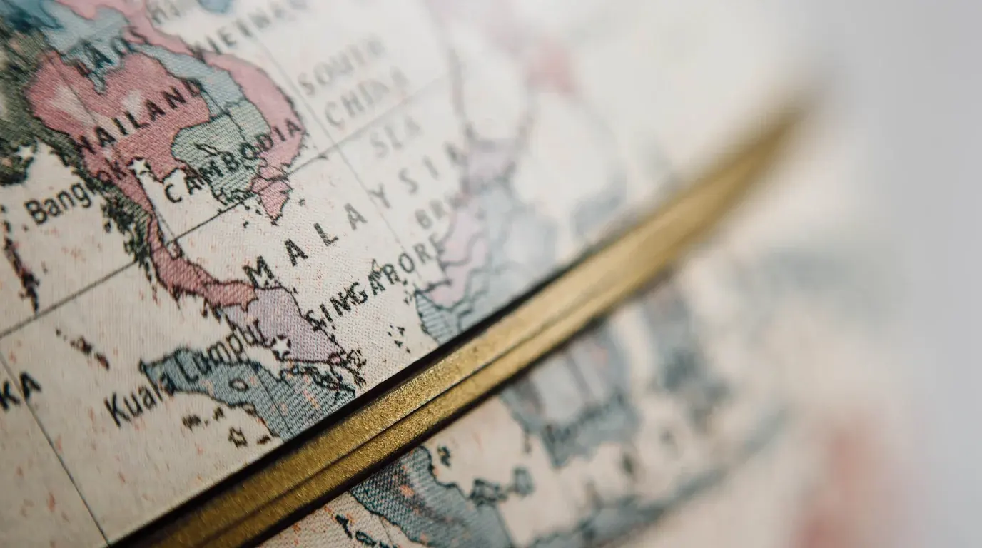 Close-up of a desk globe showing South-East Asia, its brass meridian ring crossing the map.