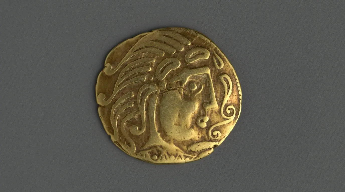 An Iron Age gold coin of the Parisii stamped with a stylised head, on a grey ground.