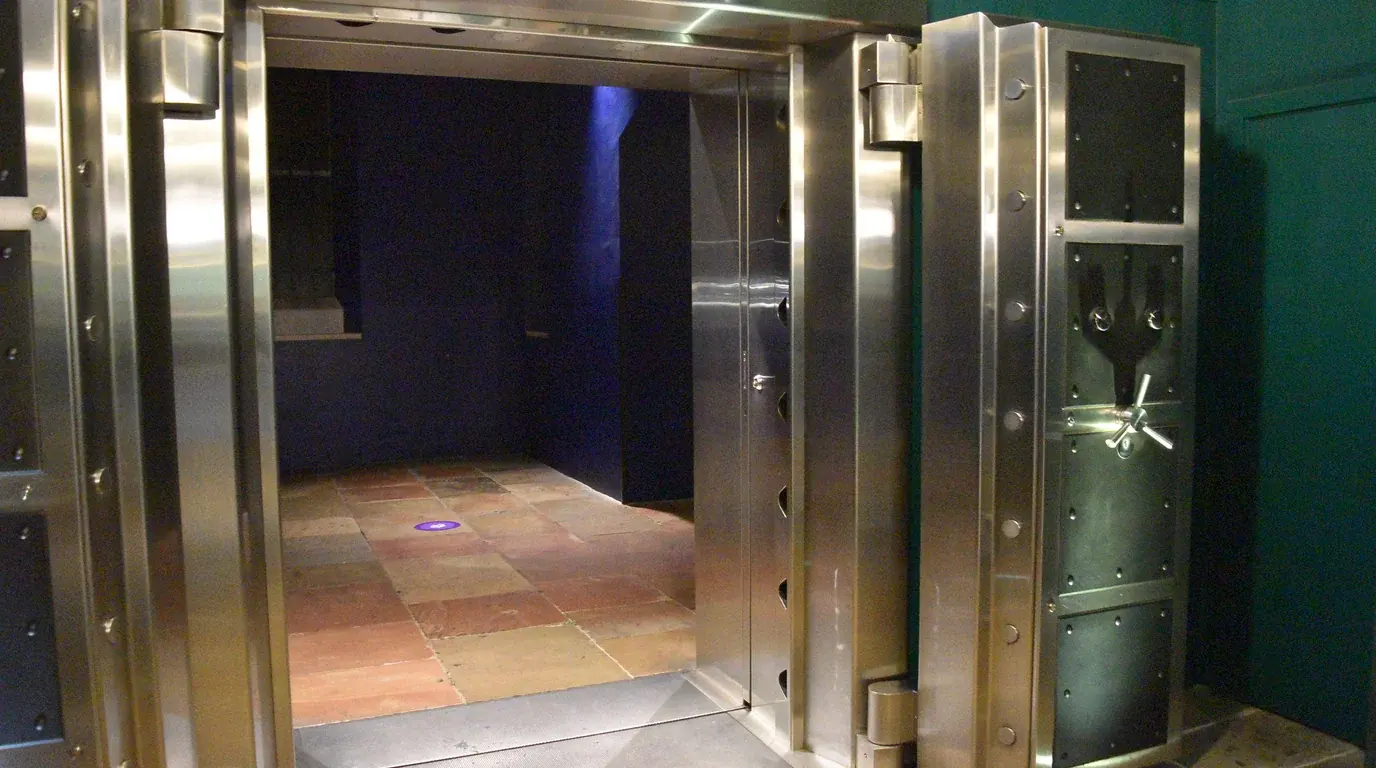 The massive open steel door of a high-security vault, a dim chamber beyond.