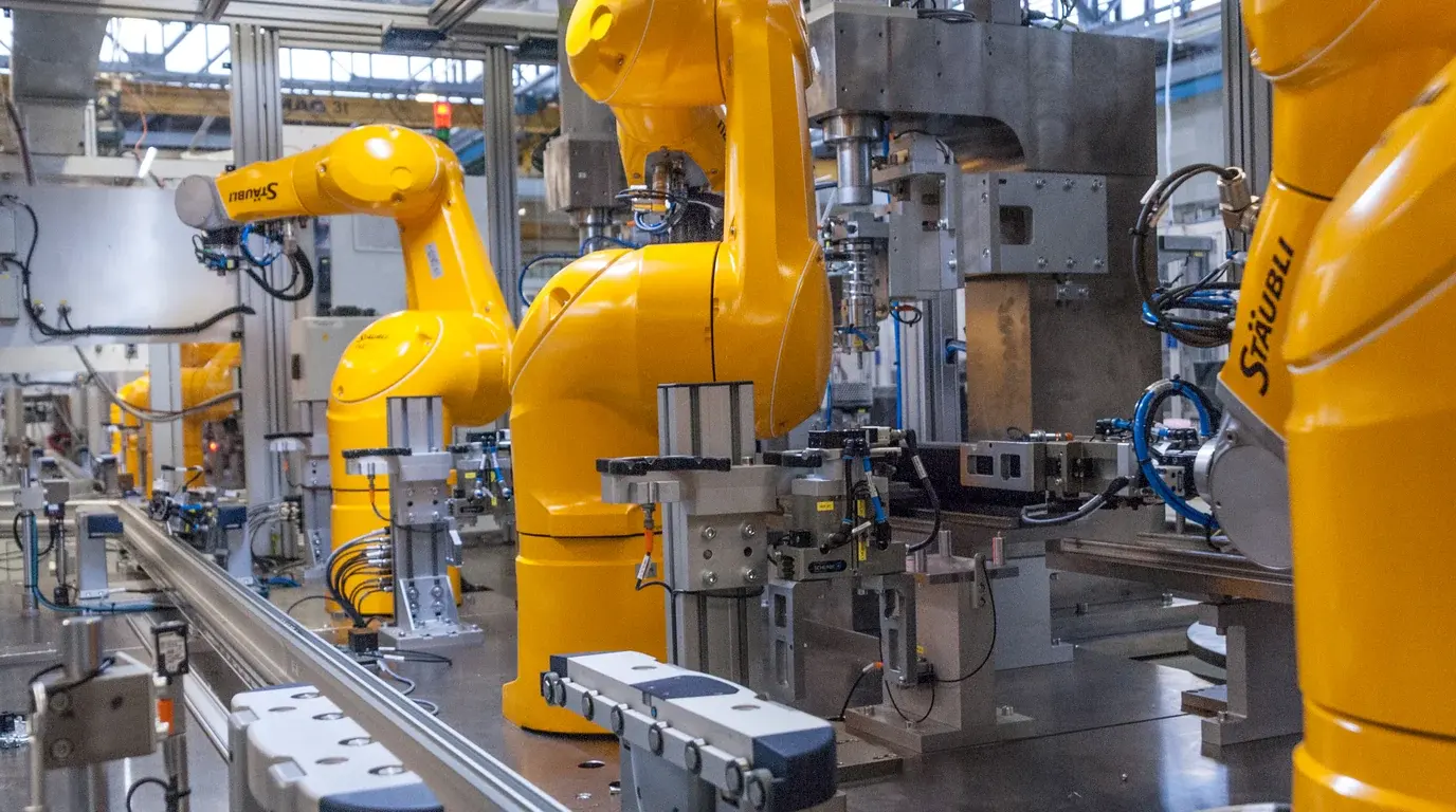 Yellow industrial robot arms working along an automated production line.