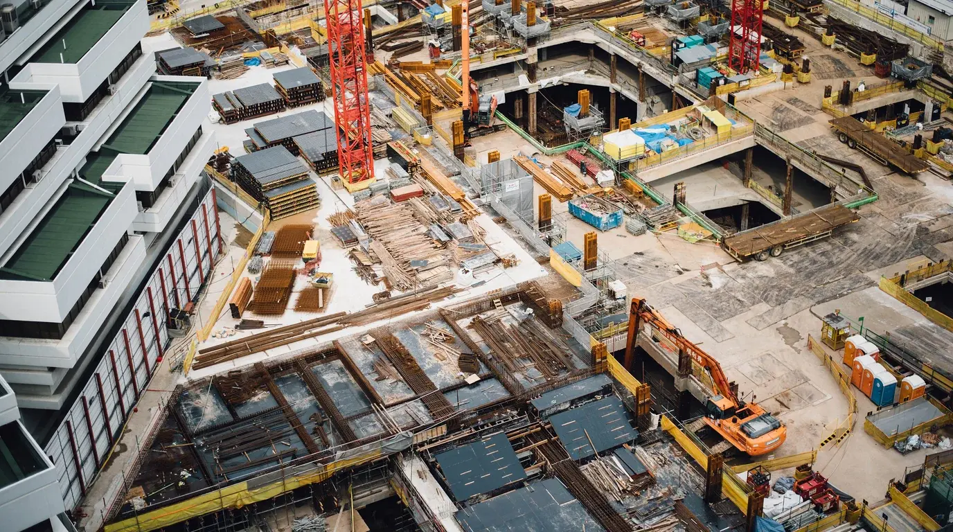 Aerial view of a large construction site, cranes and excavators working among new foundations.