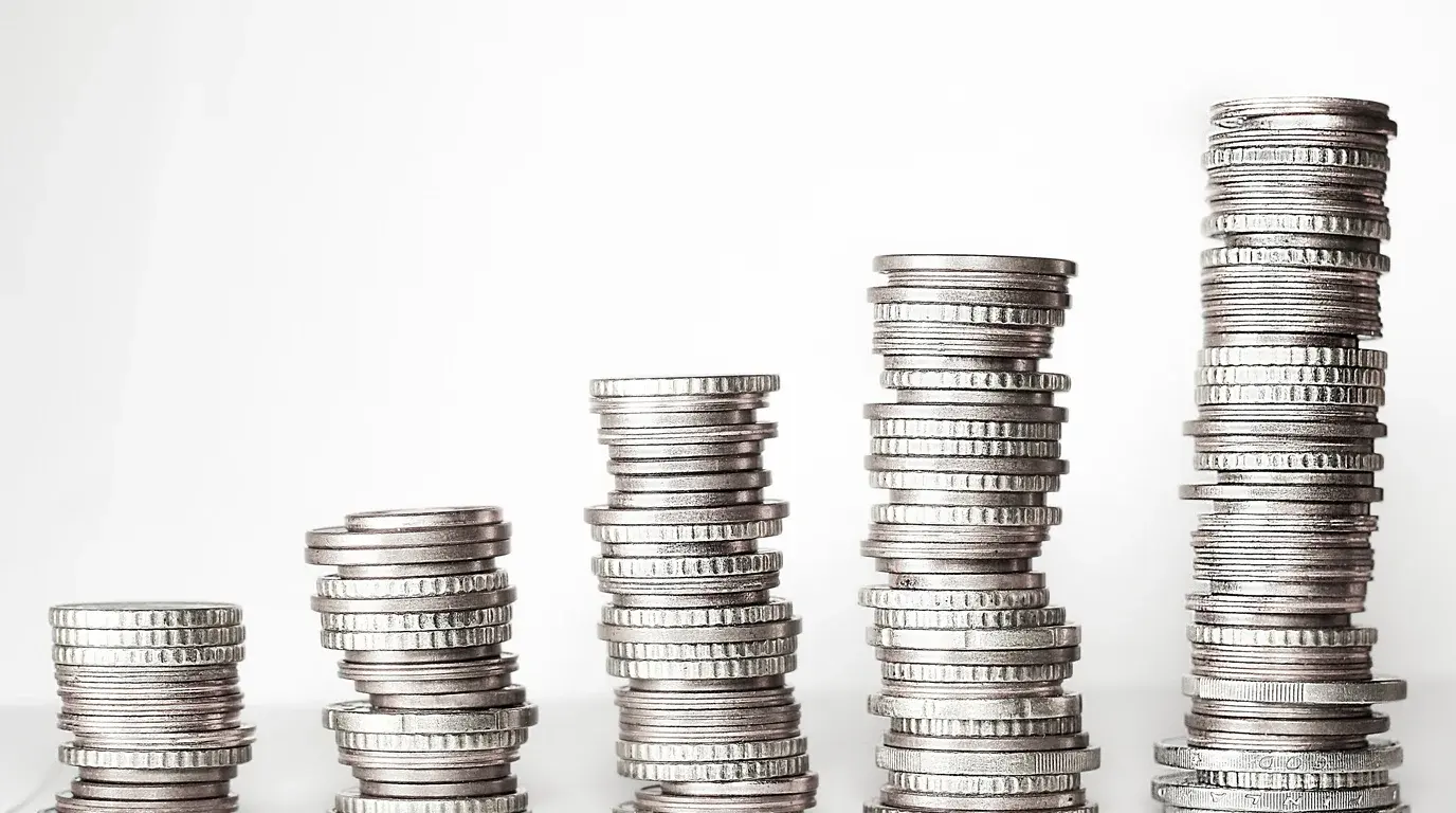 Five stacks of silver coins rising from short to tall against a white background.