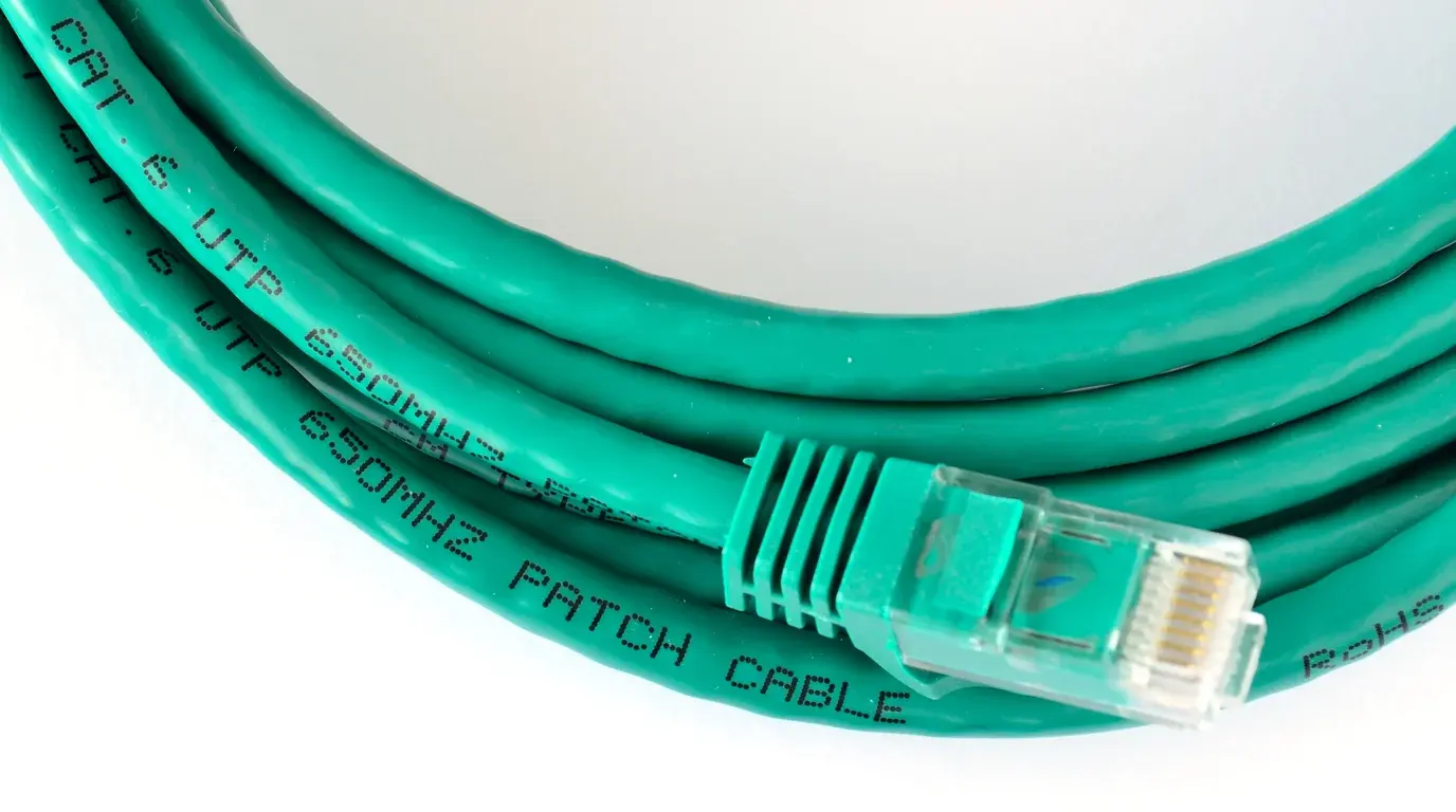 A coiled green Cat 6 network patch cable with its RJ45 plug in the foreground.