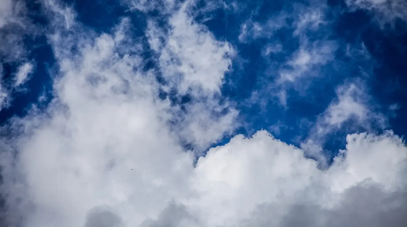 Bright white cumulus clouds piled against a deep blue sky.