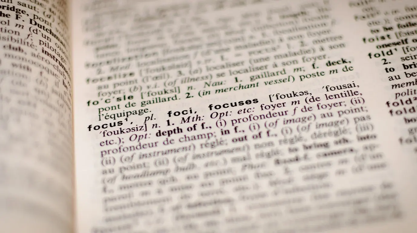 An open bilingual dictionary, the entry for focus sharp among blurred columns of definitions.