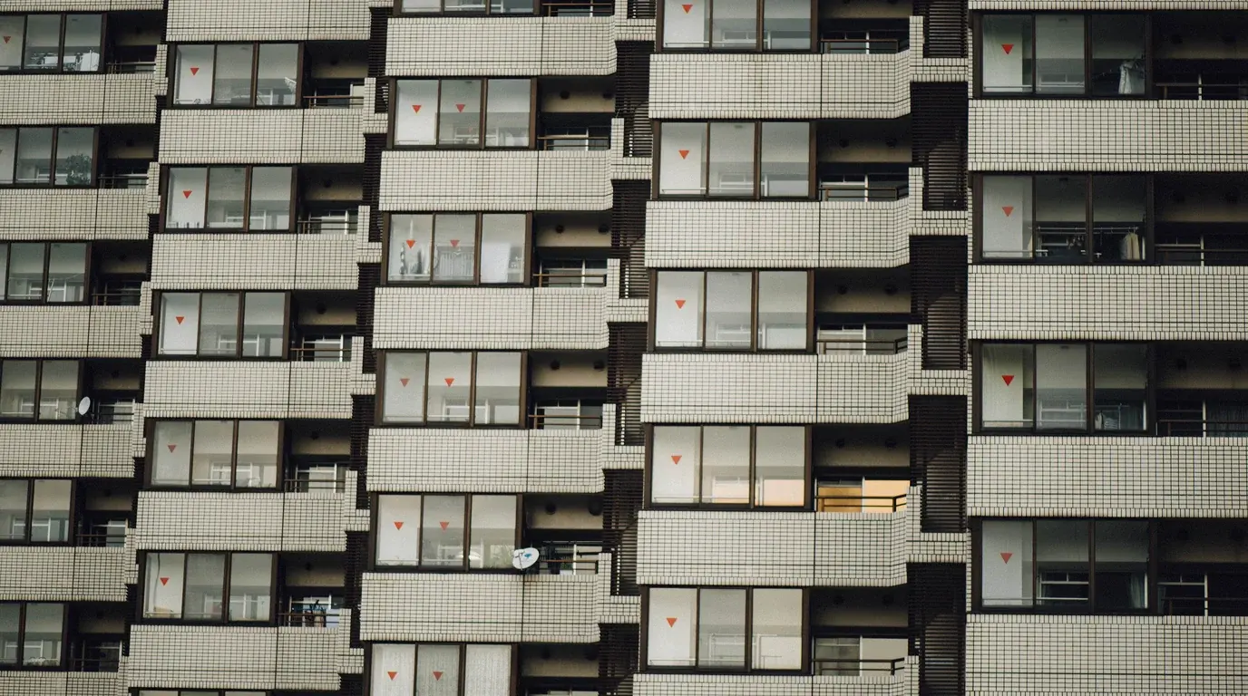 The repeating facade of an apartment block, identical tiled balconies and windows stacked floor after floor.